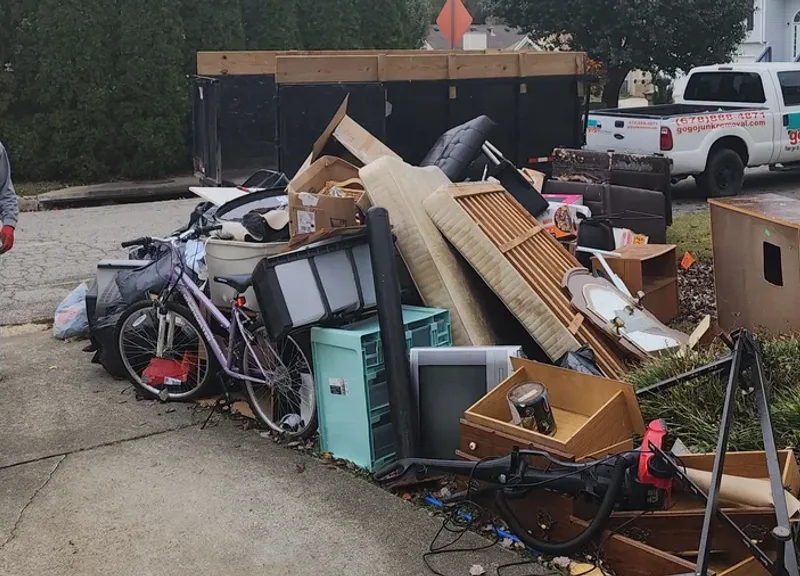 GoGo crew member standing next to large pile of household junk and furniture ready for removal