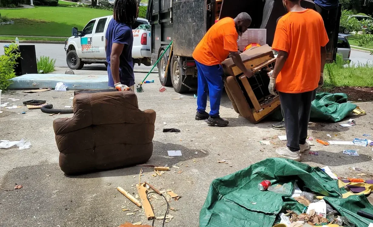 GoGo Junk Removal team handling furniture and debris on residential driveway